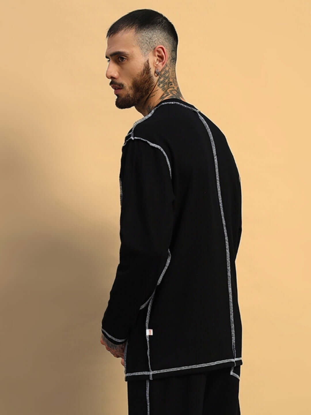 Man wearing dynamic oversized black sweatshirt made of premium cotton French terry, styled in a trendy fashion pose. Country of origin: India.