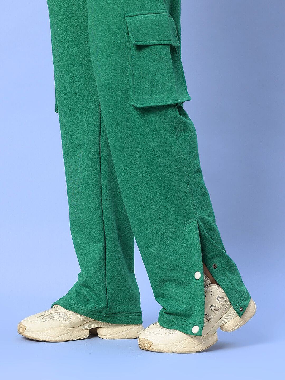Green pants with pockets and white sneakers styled for active wear.