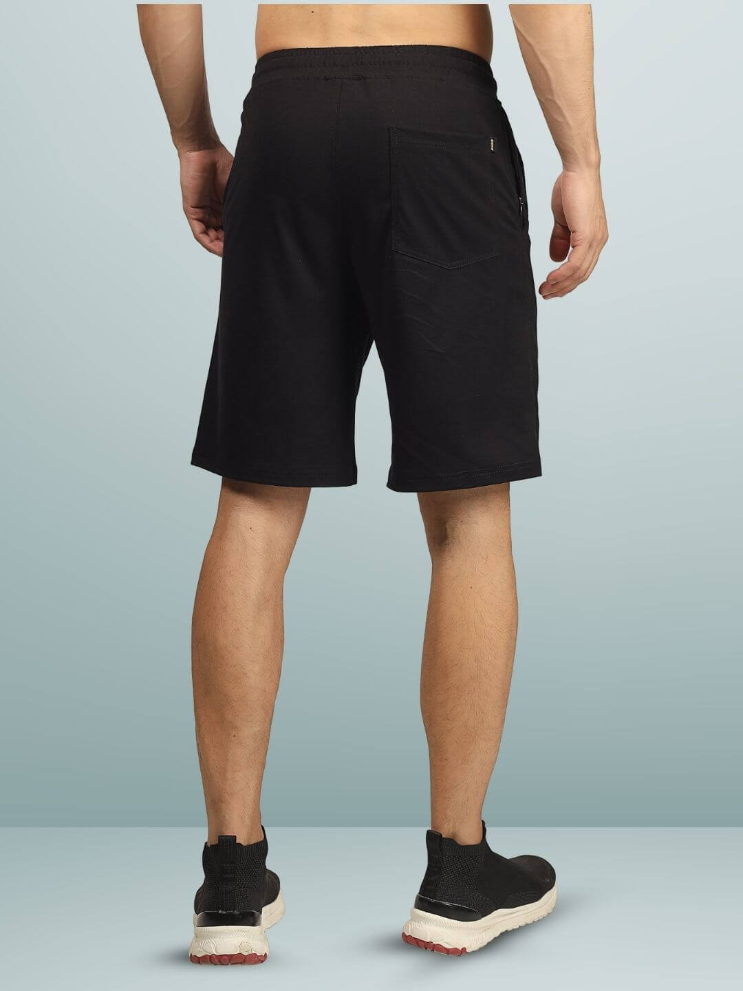 Back view of a model wearing EAT MY SHORTS regular fit black shorts, showcasing the design and fit.