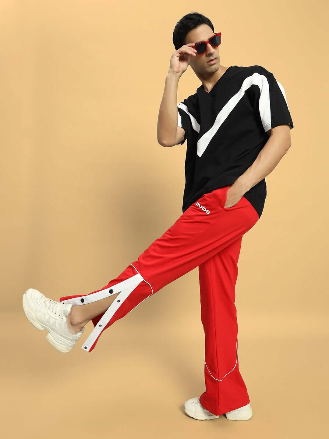 Model wearing EDDIE CONTRAST JOGGERS in vibrant red, styled with a black and white top and red sunglasses, highlighting modern casual fashion.