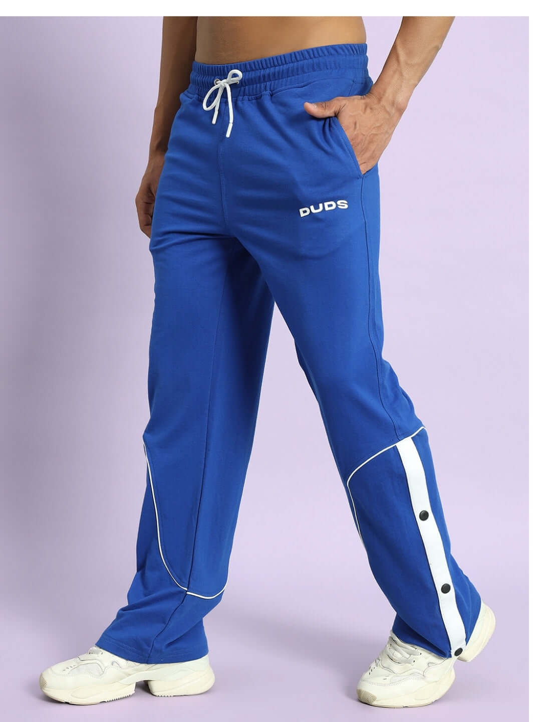 Man wearing Eddie Contrast Joggers in royal blue with white sneakers on a lavender background