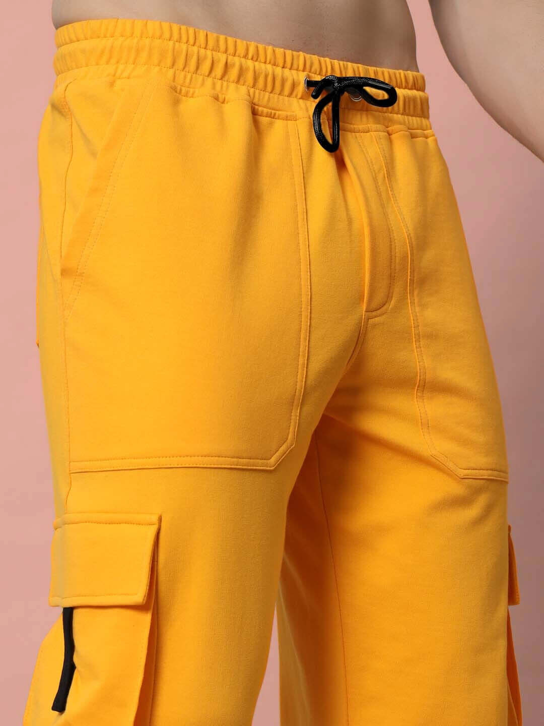 Close-up of yellow relaxed fit cargo pants with drawstring and side pockets by EDIFICE, designed for comfortable and customizable wear.