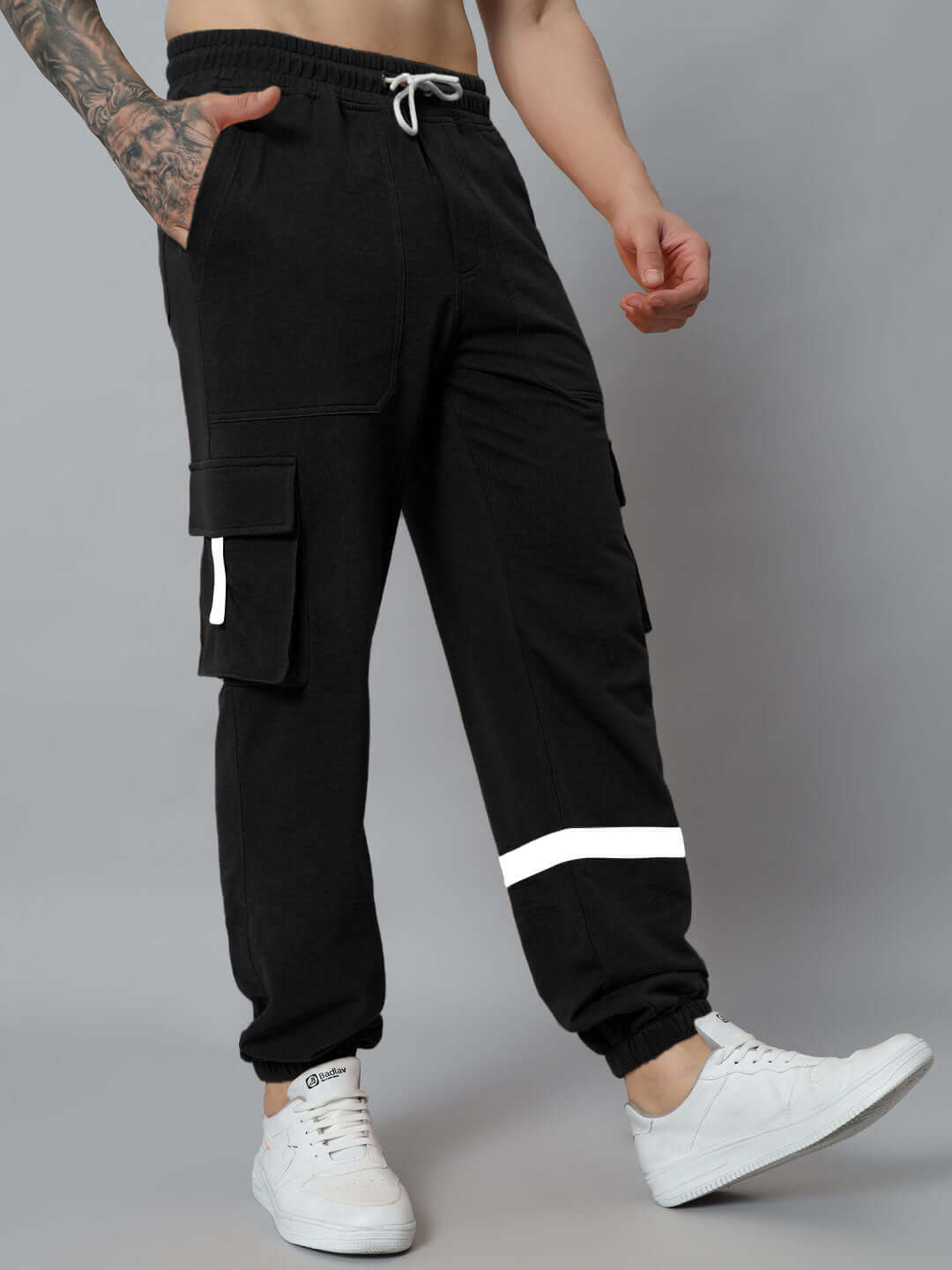 Person wearing black EDIFICE RELAXED FIT CARGO PANT with white sneakers, showcasing multiple pockets and a comfortable fit.