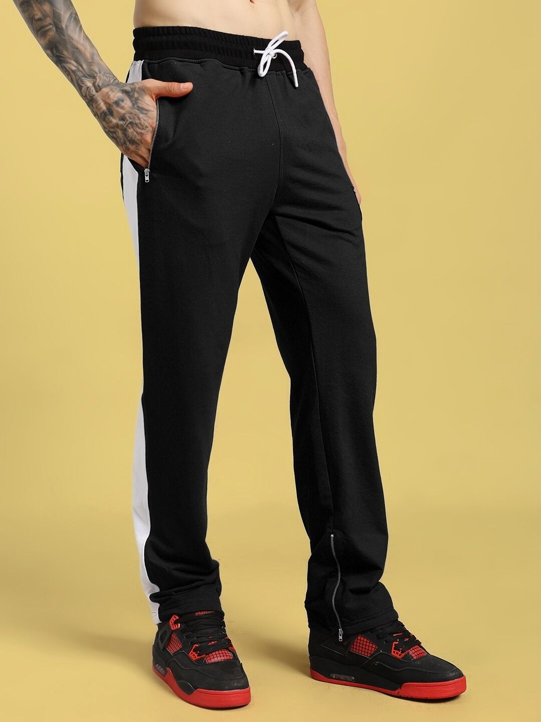 Person wearing ELEGANT RELAXED-FIT JOGGERS BLACK with red sneakers on yellow background