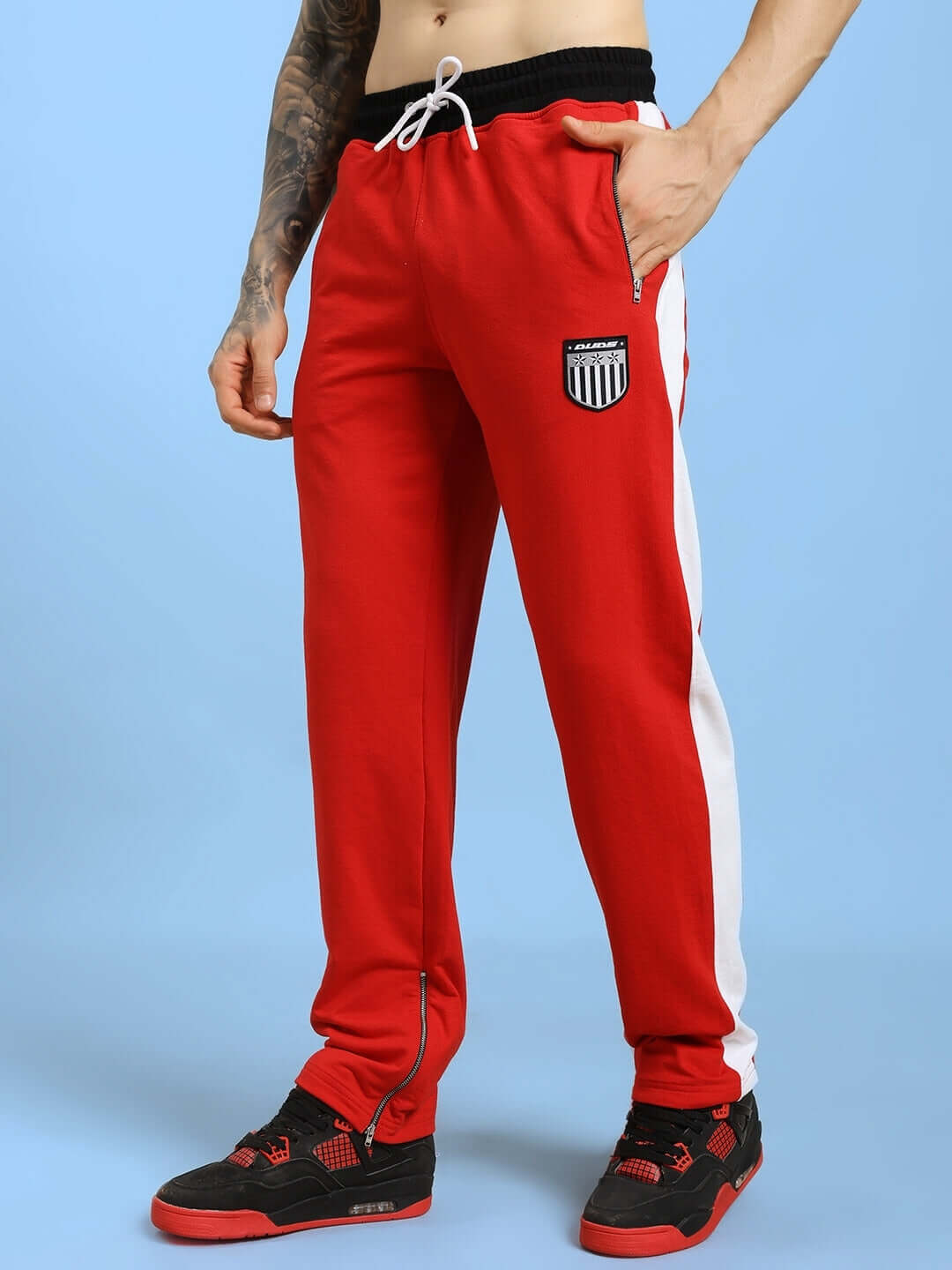 Model wearing Elegant Relaxed-Fit Joggers Red with casual sneakers on a blue background.