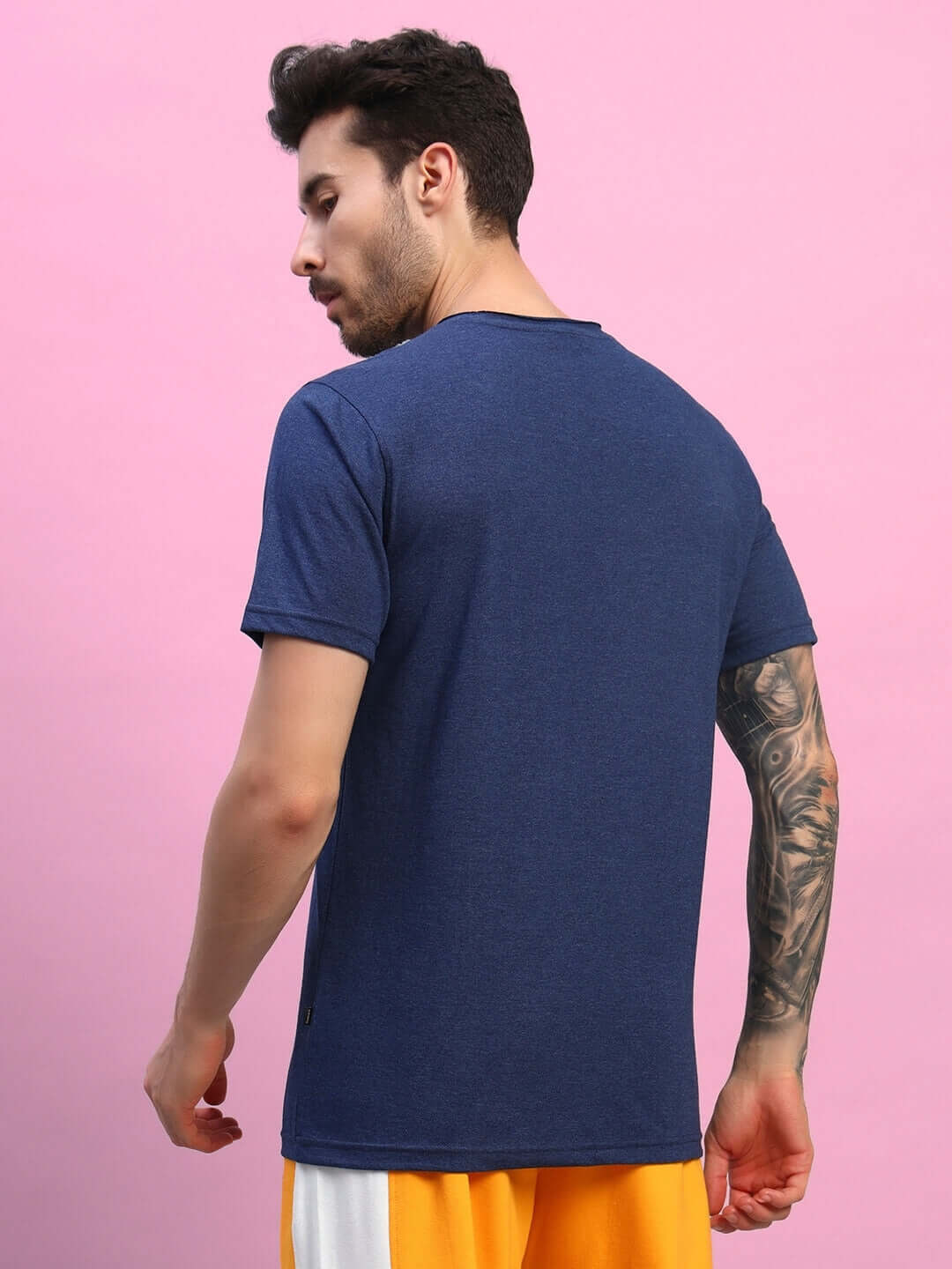 Back view of model wearing ELEX REGULAR FIT T-SHIRT NAVY BLUE against pink background