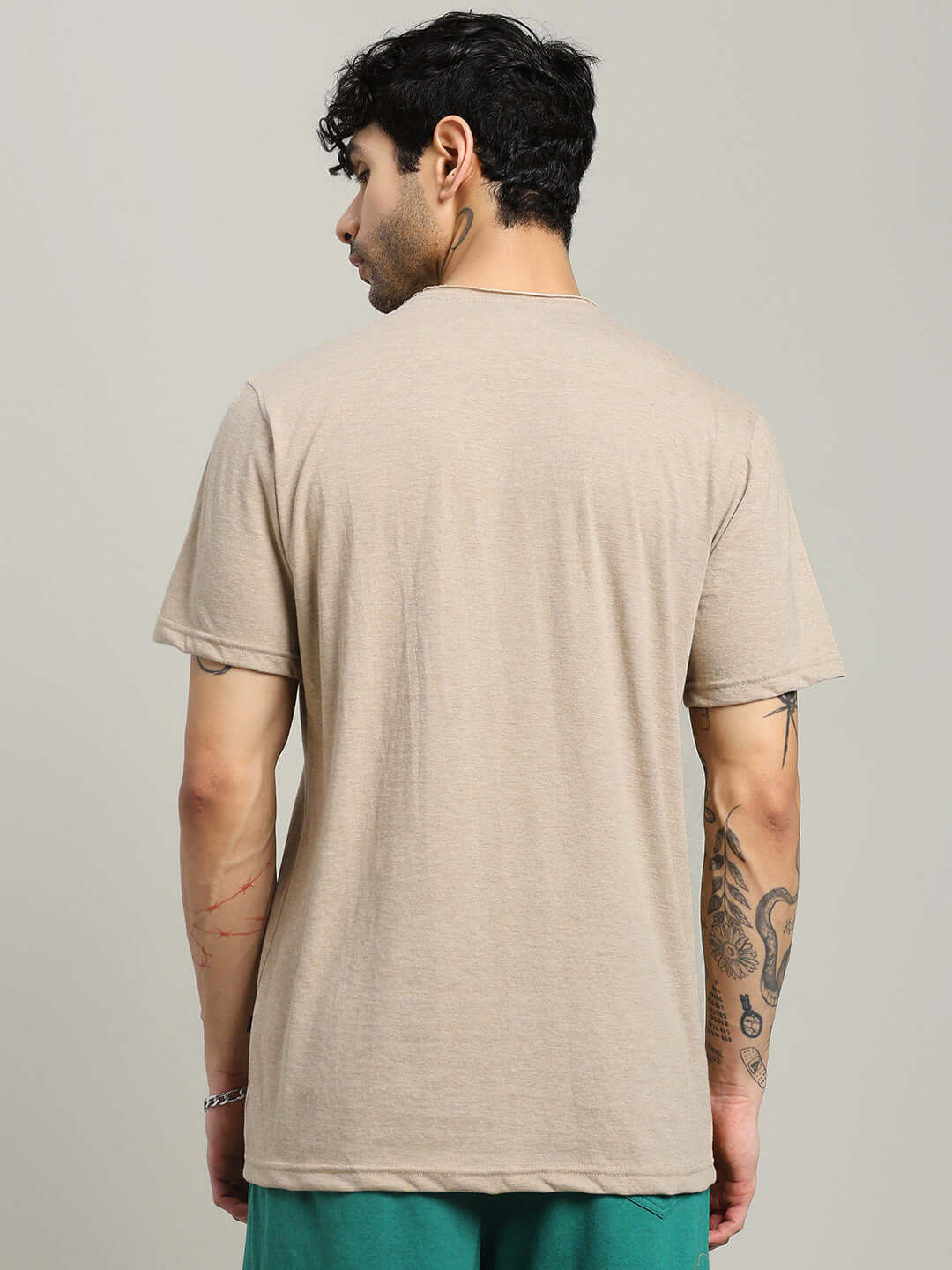 Back view of a man wearing the ELEX REGULAR FIT T-SHIRT BEIGE, showcasing its soft premium cotton fabric and versatile design.