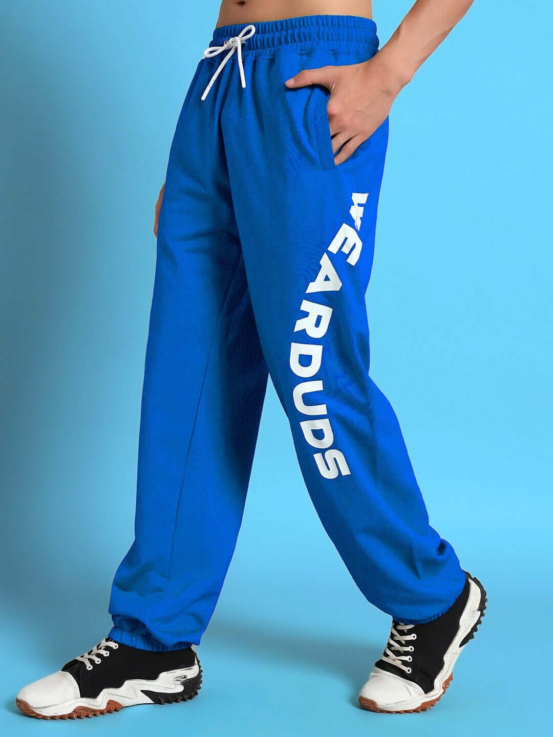 Model wearing Ellen Relaxed Fit Jogger in blue by DUDS, showcasing casual style with white text detail on pant leg.