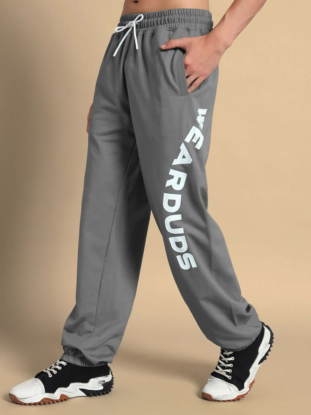 Man wearing grey Ellen relaxed fit jogger by DUDS, featuring comfortable design and bold white 'WEAR DUDS' lettering on the side.