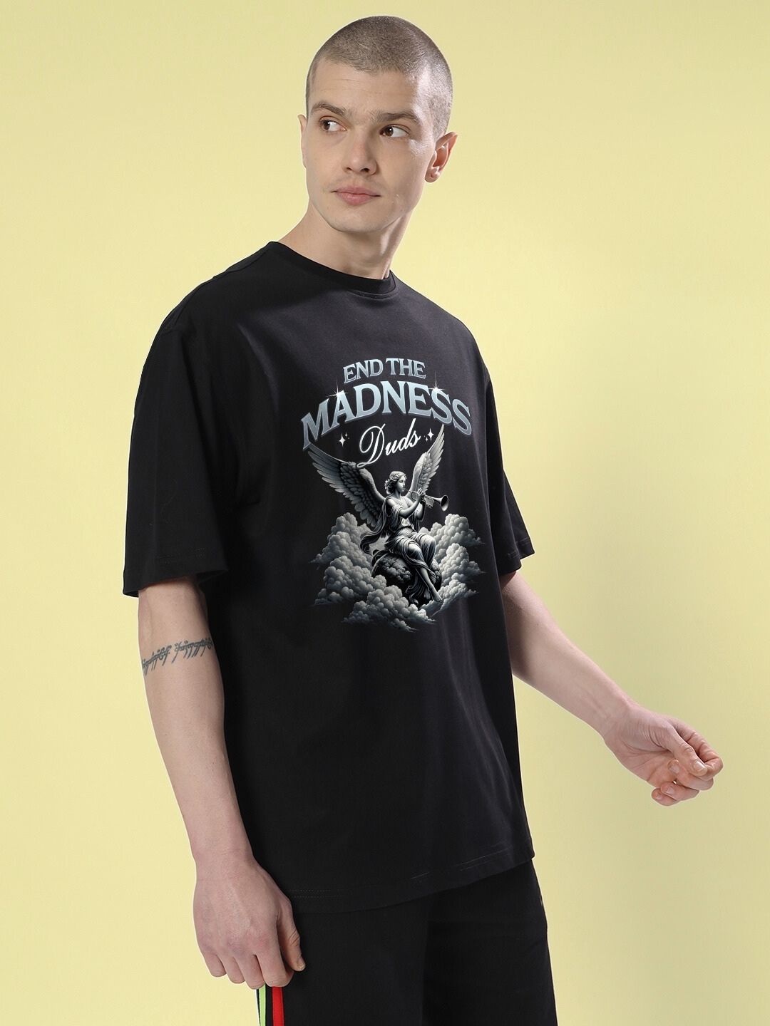 Man wearing END THE MADNESS OVER-SIZED T-SHIRT BLACK with graphic print, showcasing bold streetwear style and relaxed fit.