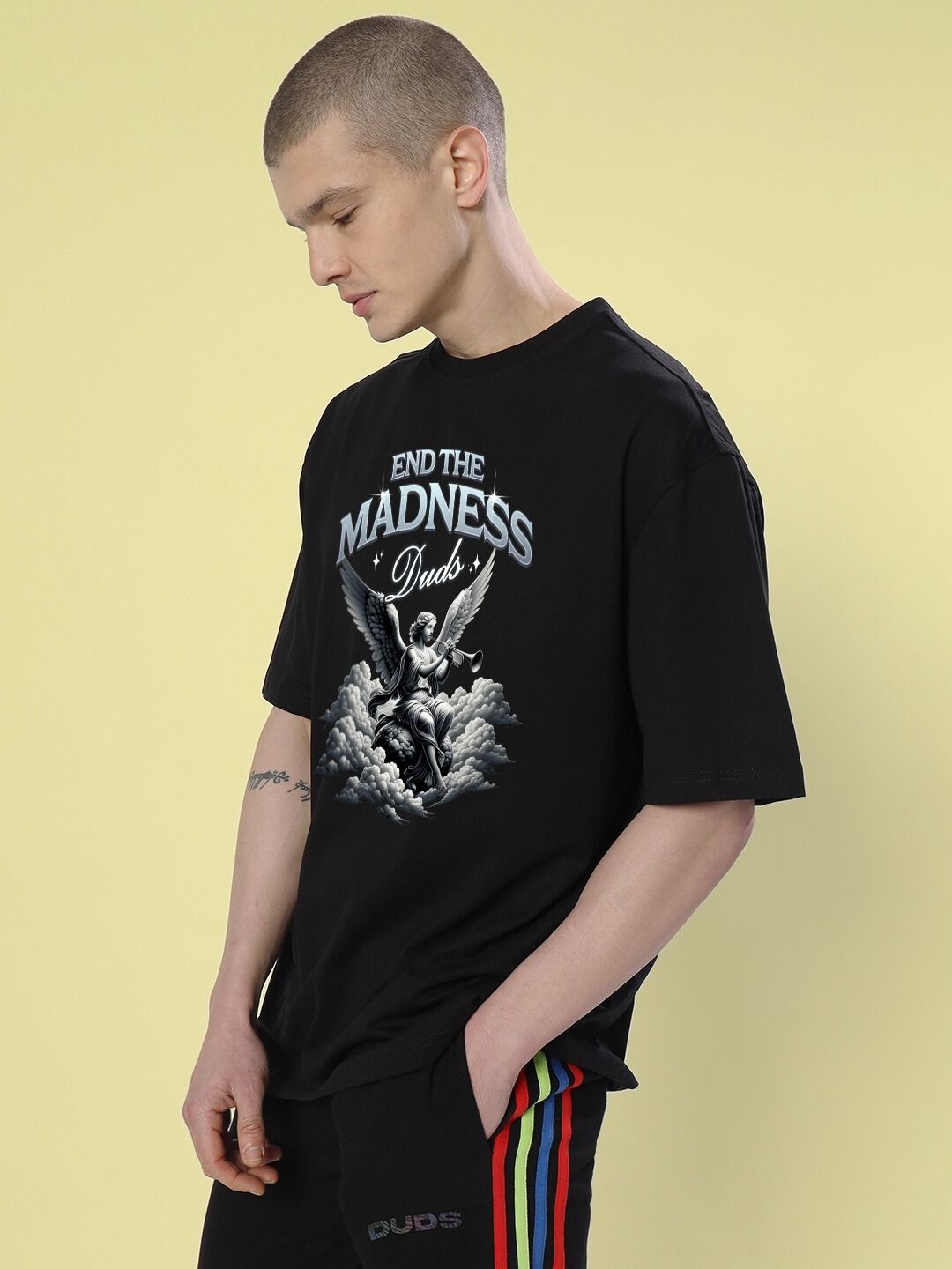 Model wearing END THE MADNESS OVER-SIZED T-SHIRT BLACK with bold graphic on front, streetwear fashion.