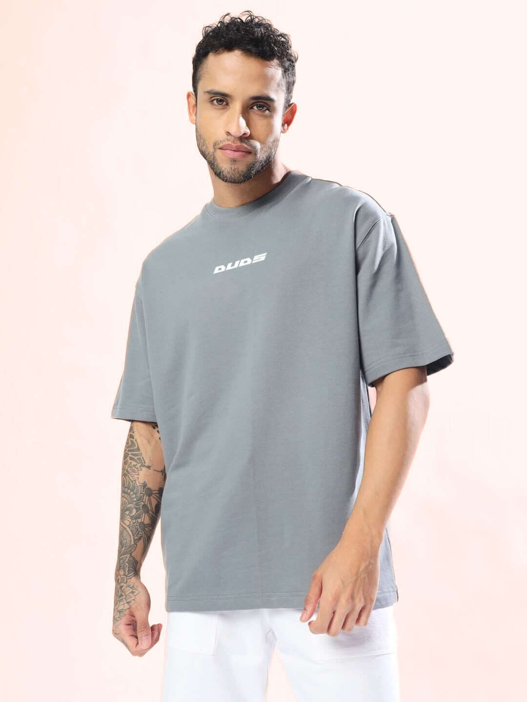 Model wearing grey oversized 'Enjoy the Wind' t-shirt, custom fit options available. Unique design by DUDS.