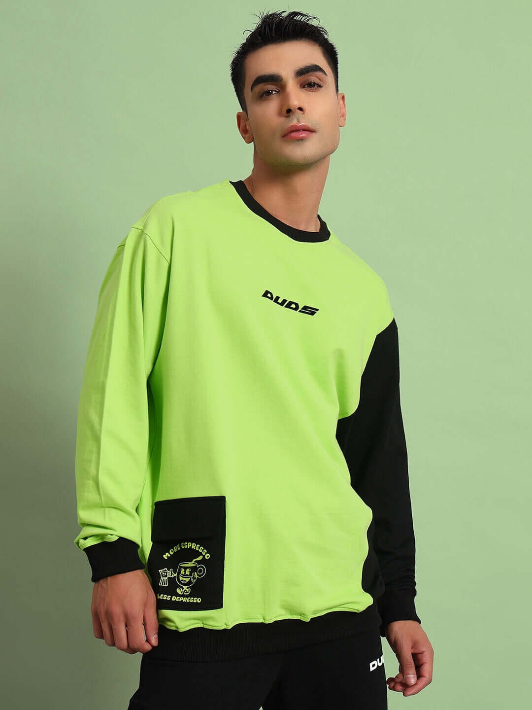 Model wearing neon green and black oversized sweatshirt with pocket detail, made from premium cotton French terry Lycra. ESPRESSO brand.