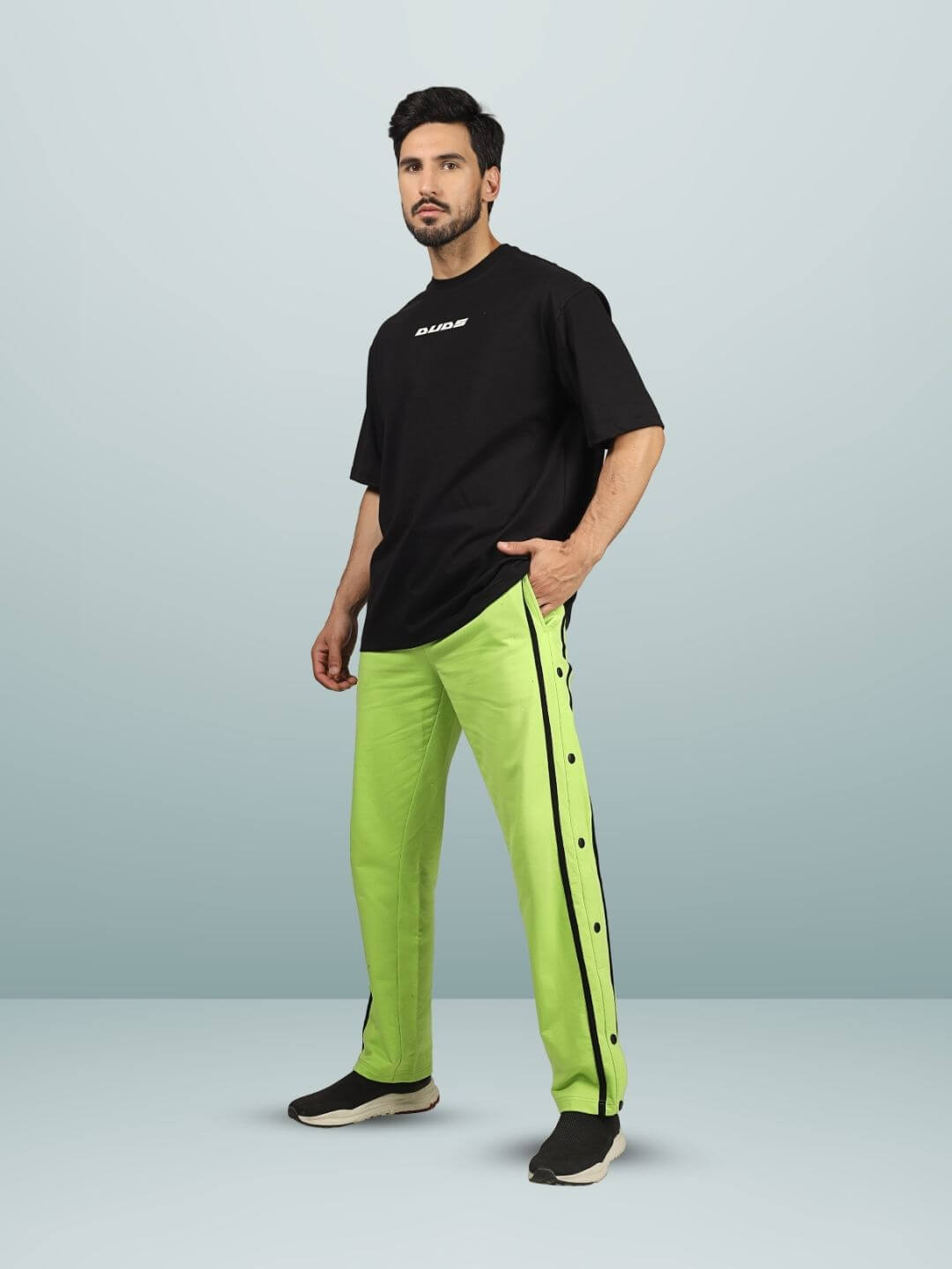 Model wearing ETCETERA oversized black T-shirt with neon green pants, showcasing custom fit option available for prepaid orders.