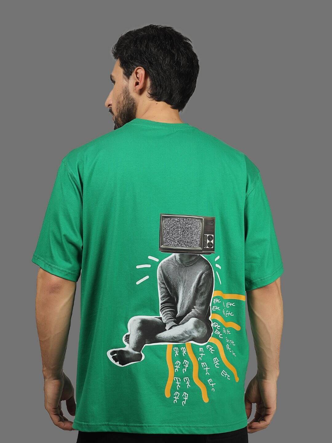 Man wearing green oversized T-shirt with TV head design, part of customizable ETCETERA collection by DUDS.