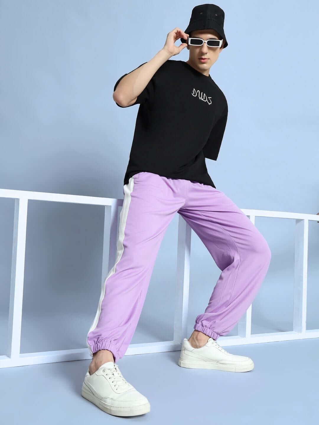 Model wearing Euphoria Joggers in lavender-white, styled with black shirt and white sneakers, showcasing relaxed fit and modern design.