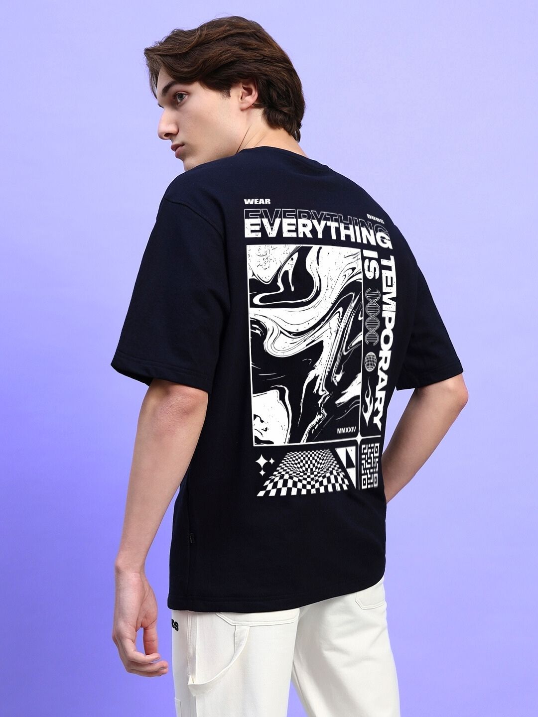 Back view of EVERYTHING IS TEMPORARY OVER-SIZED T-SHIRT BLACK with abstract design, worn by model against purple background.