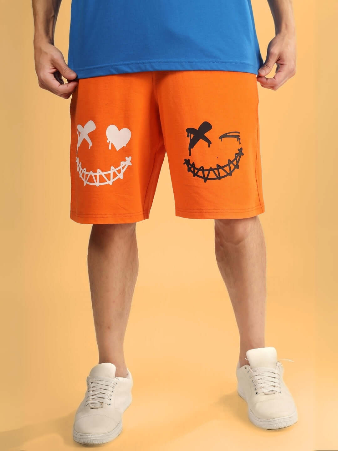 Man wearing orange shorts with evil smile graphic, regular fit, customized sizing options available. Perfect for casual wear.