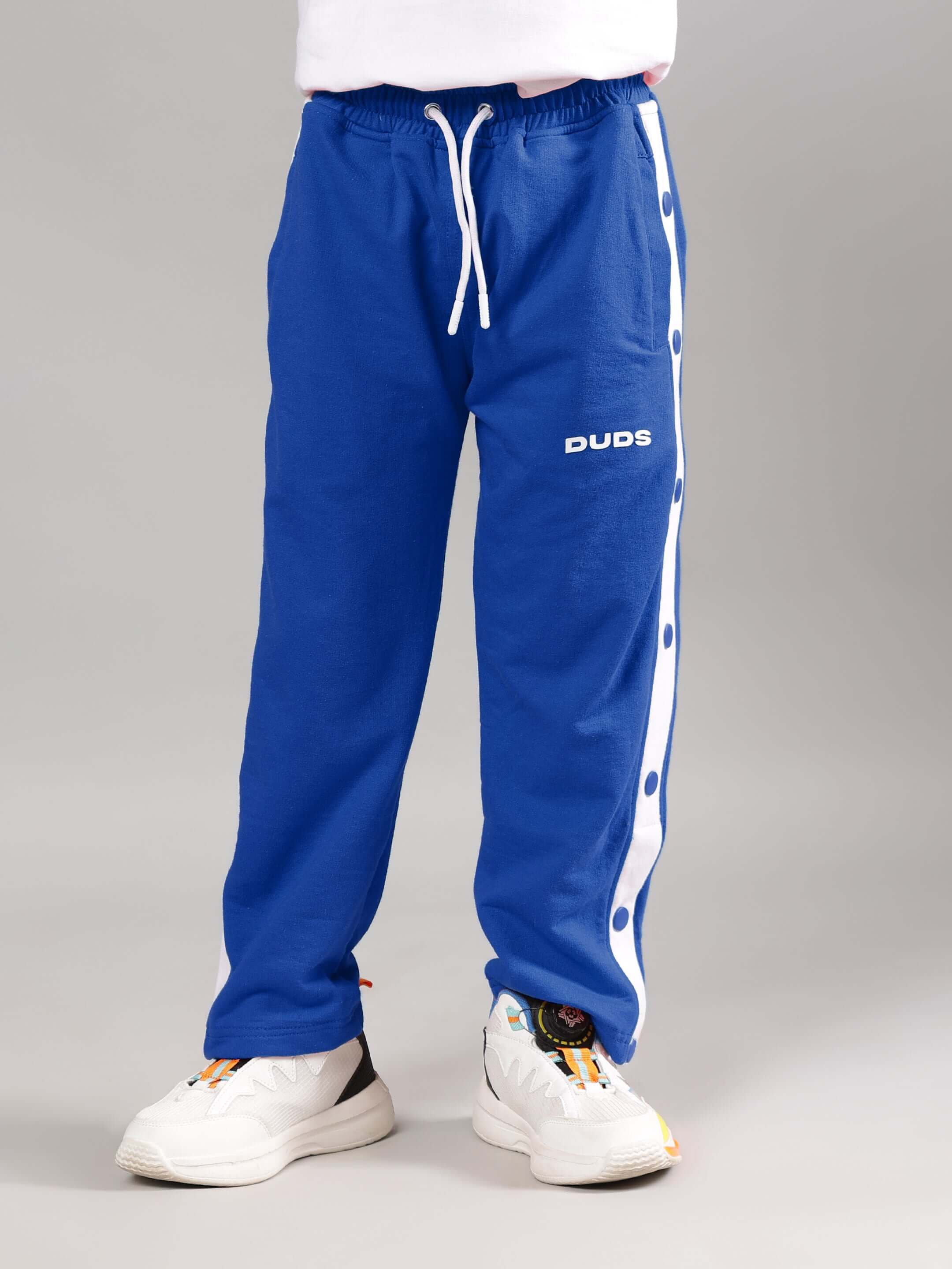 EZEL JOGGER FOR BOYS & GIRLS BLUE with white side buttons, modeled by child wearing DUDS sneakers.