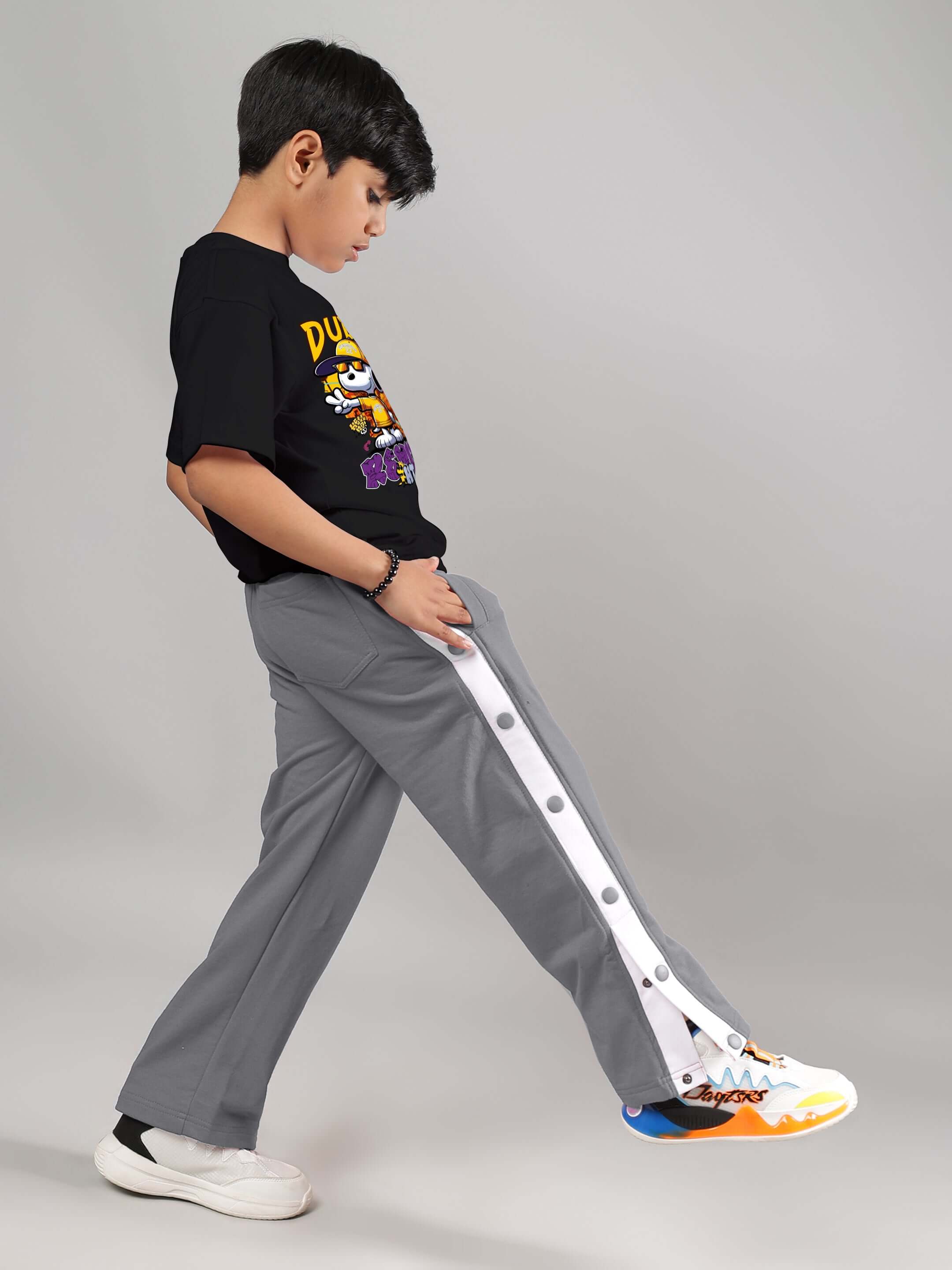 Child wearing EZEL JOGGER FOR BOYS & GIRLS GREY showing side profile in stylish pose, perfect for casual wear.