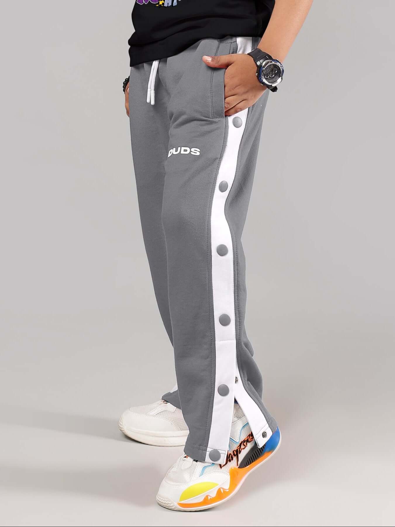 Child wearing EZEL JOGGER FOR BOYS & GIRLS GREY with white side stripes and sneakers.