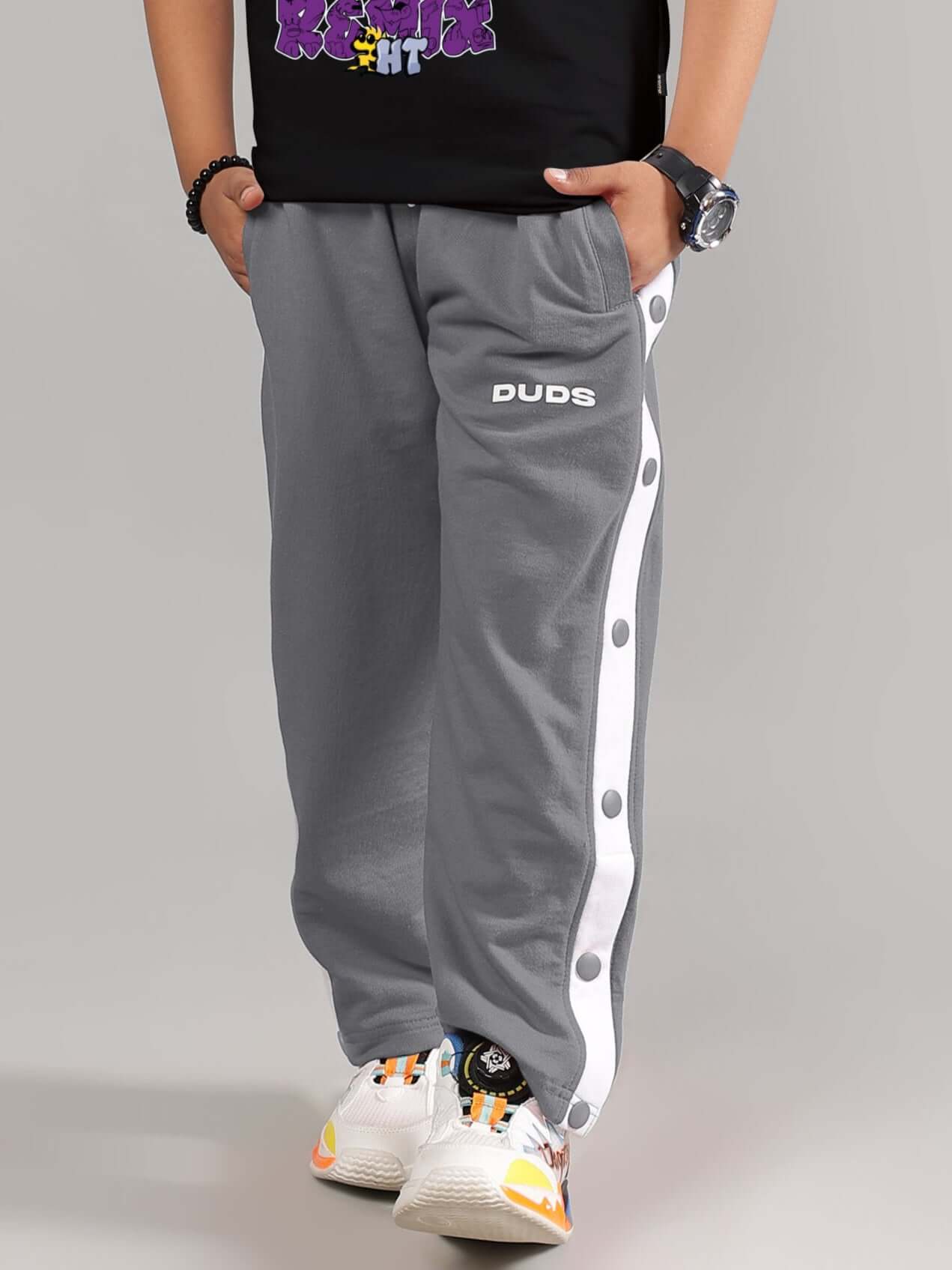 Child wearing grey EZEL JOGGER FOR BOYS & GIRLS with button detail and DUDS logo.