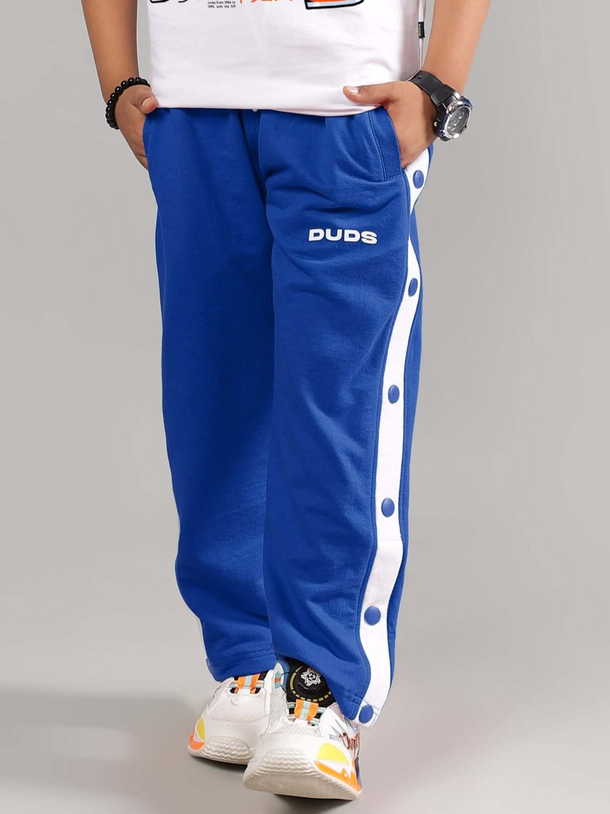 Child wearing EZEL JOGGER FOR BOYS & GIRLS BLUE with white stripes and button details, made by DUDS for custom fit.