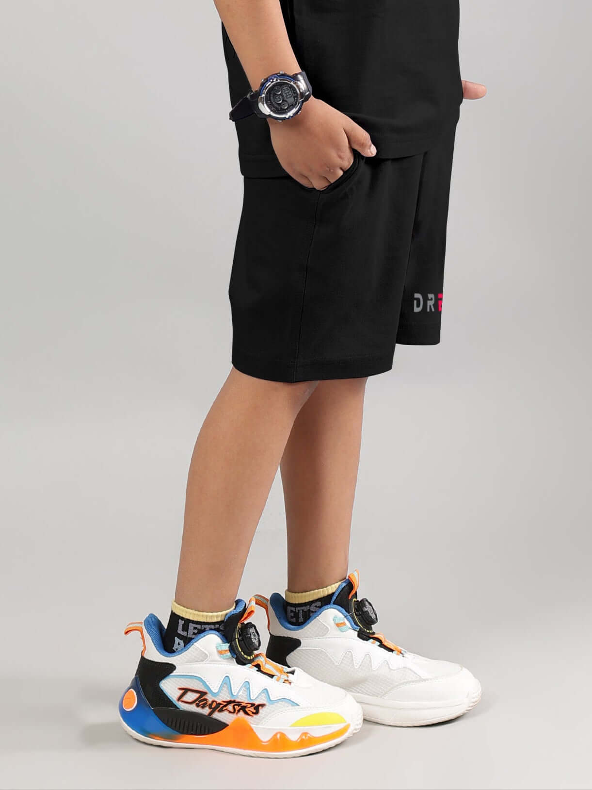 Child wearing Fancy Dream Shorts for Boys & Girls in Black with colorful sneakers and a wristwatch.