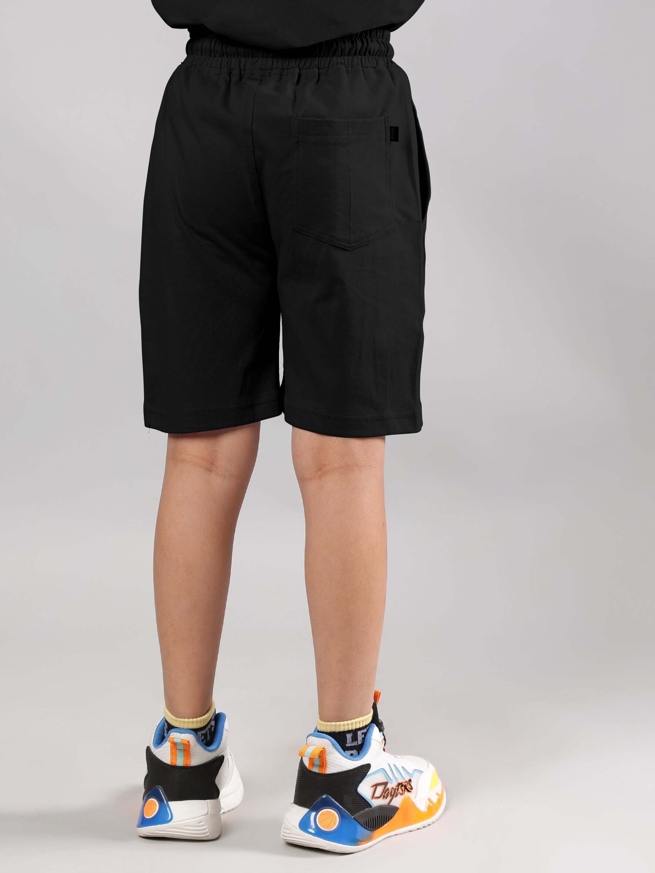 Child wearing Fancy Dream Black Shorts, back view, paired with colorful sneakers.