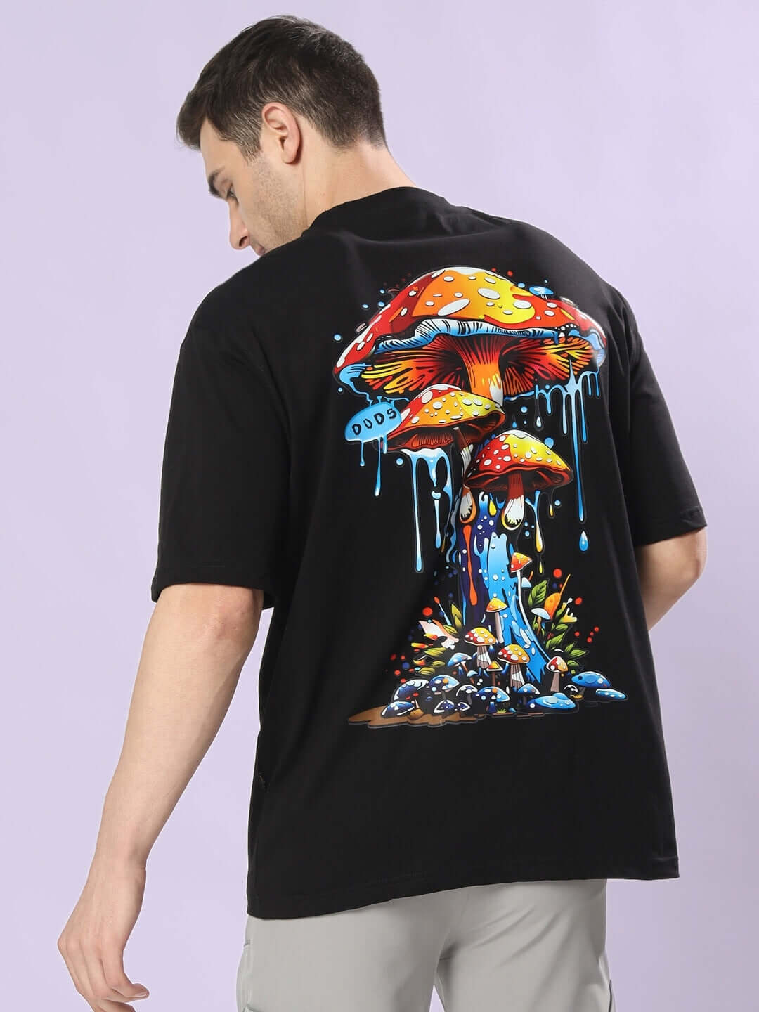Man wearing fantasy mushroom over-sized black T-shirt with colorful graphic design; unique custom fit option available for prepaid orders.
