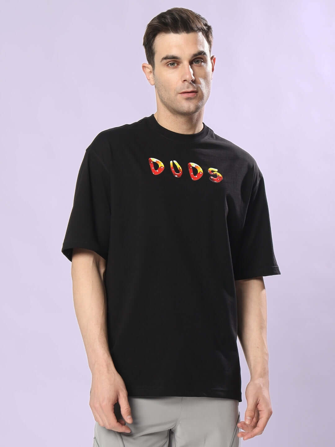 Model wearing Duds Fantasy Mushroom Over-Sized T-Shirt in black with colorful logo design, showcasing casual fashion style.