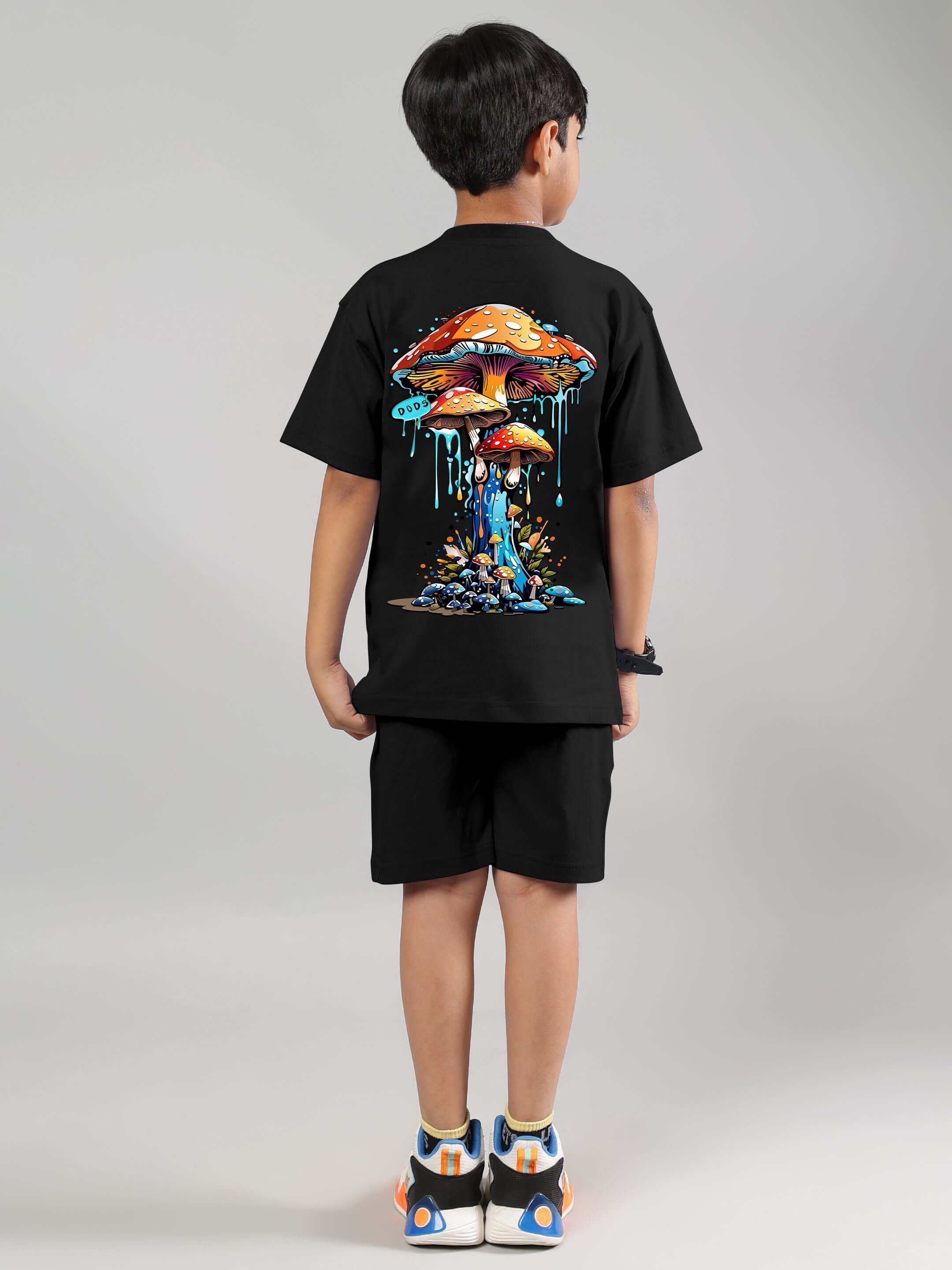 Child wearing black fantasy mushroom co-ord outfit, made by DUDS, featuring colorful psychedelic mushroom artwork, back view.