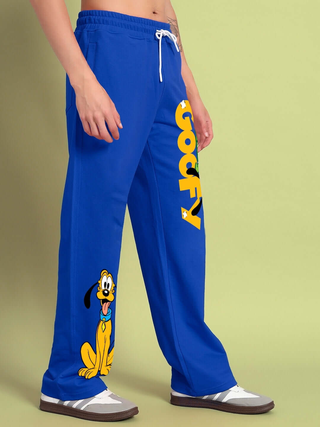 Blue relaxed fit jogger with 'Goofy' text and cartoon graphic, worn by a person on a light green background.