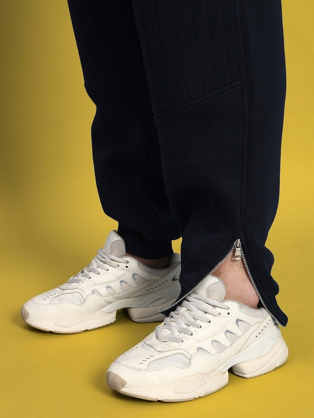 Person wearing FIGHT NIGHT FLEECE CO-ORD NAVY BLUE pants with white sneakers, showing zip detail.
