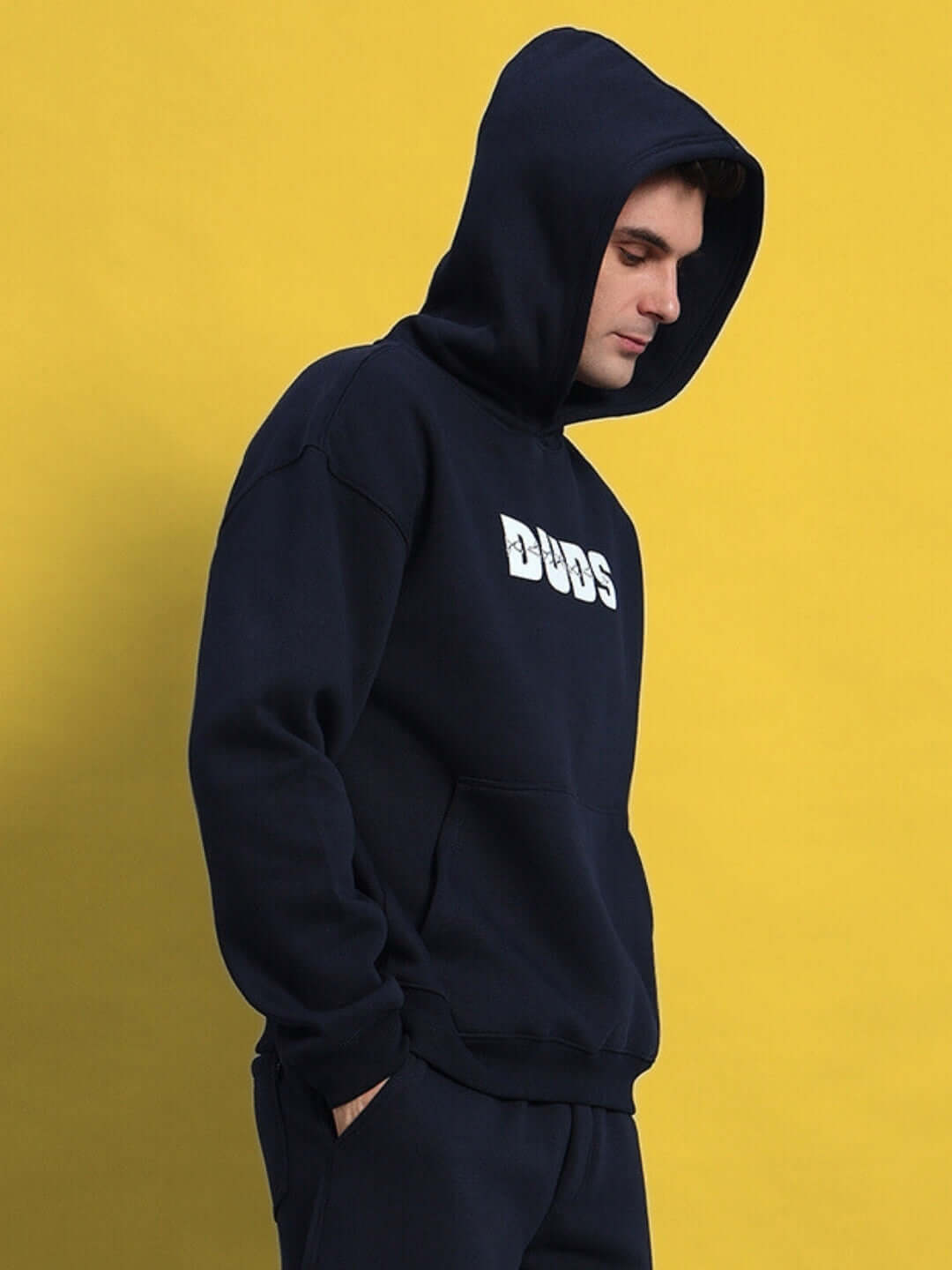 Man wearing Fight Night fleece hoodie in navy blue with logo, standing against a yellow background.