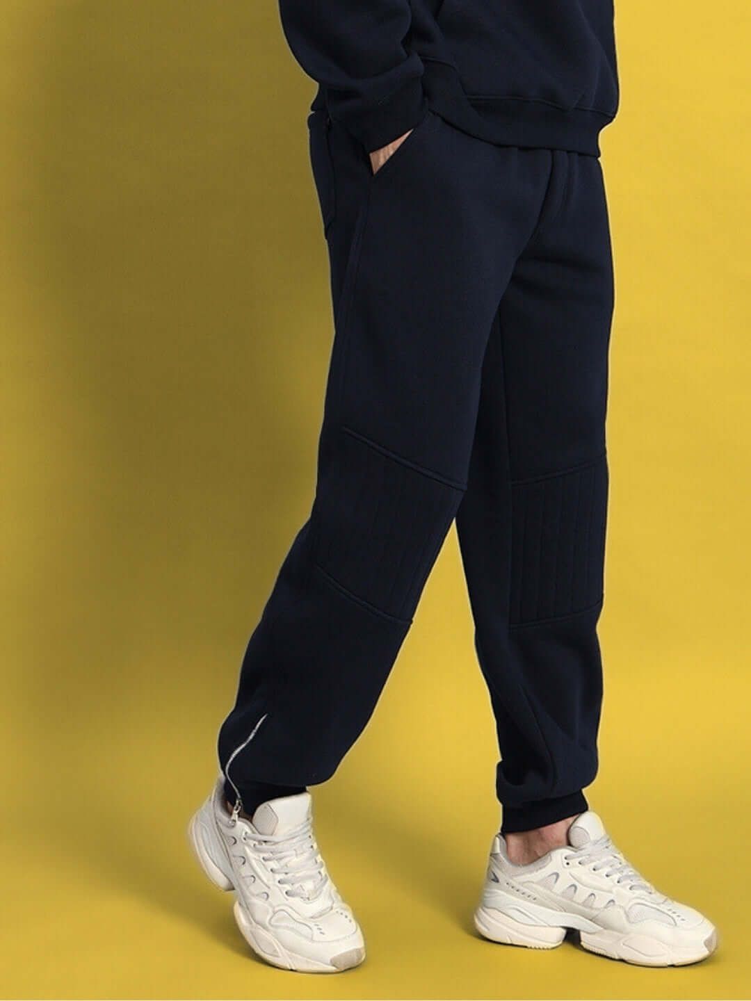 Navy blue Fight Night fleece joggers worn with white sneakers against a yellow background, showcasing casual athletic style.