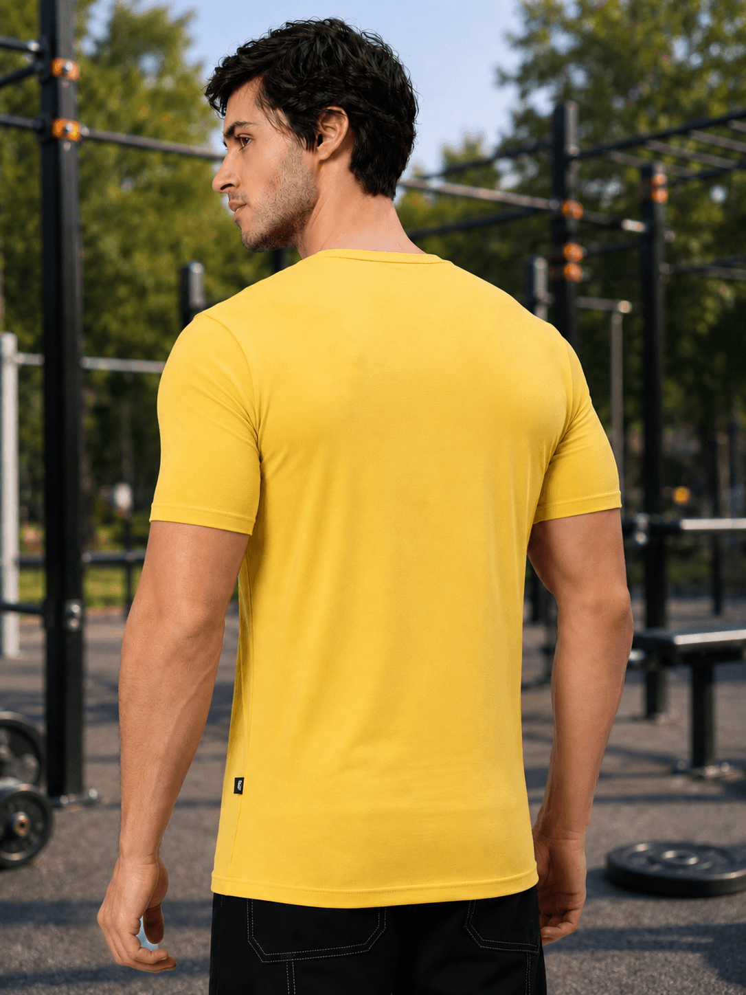 Man wearing BEDROCK FIT REGULAR FIT T-SHIRT YELLOW in an outdoor gym setting.