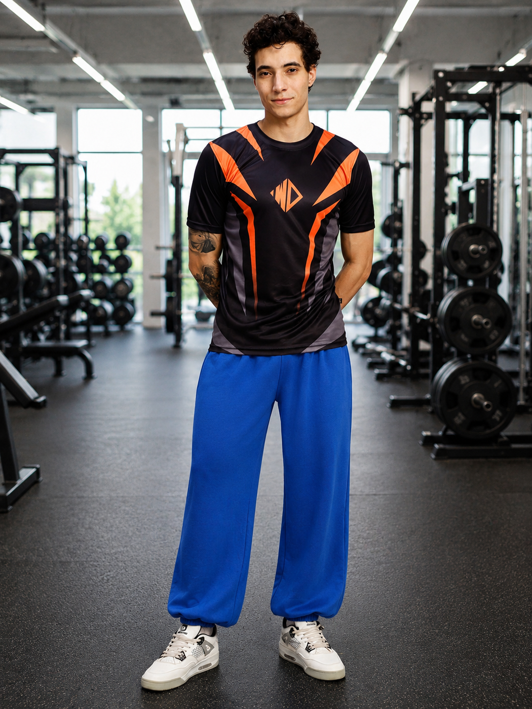 Image of a model wearing COOLFIT BAGGY LOOSE FIT JOGGER BLUE with a black and orange shirt in a gym setting.