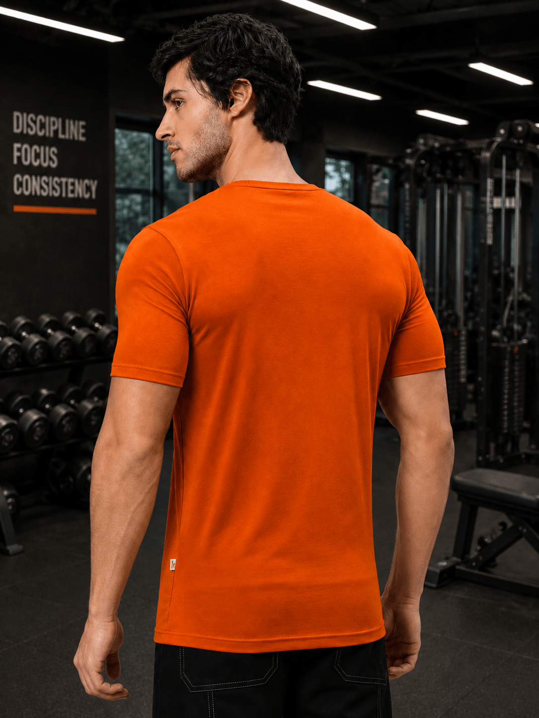 BEDROCK FIT REGULAR FIT T-SHIRT ORANGE worn by a fitness model in a gym setting.