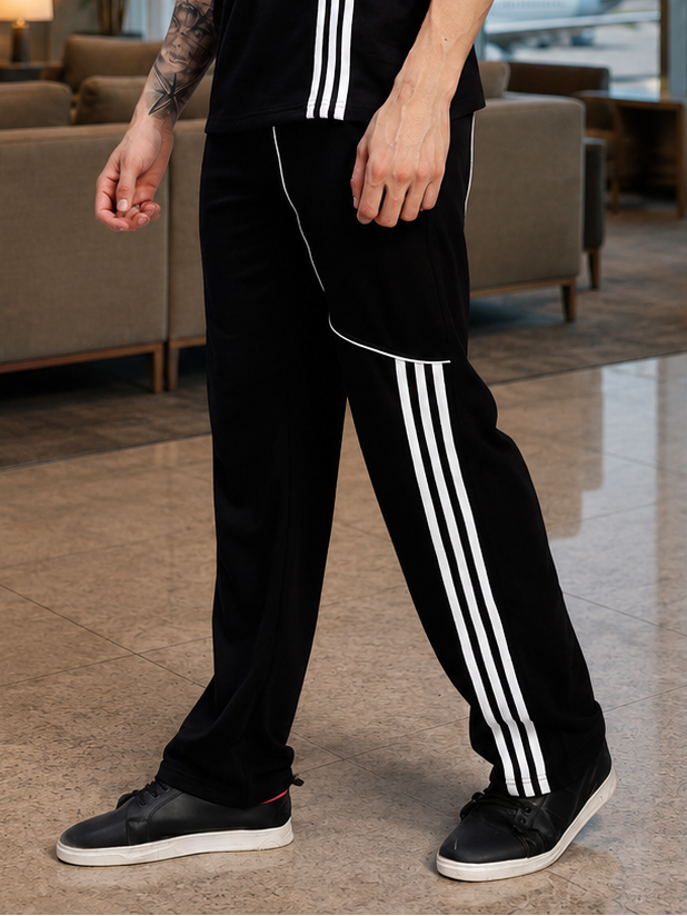 YOUTH CONTREST PIPING JOGGERS BLACK worn by a model with a stylish outfit and sneakers in a modern indoor setting.
