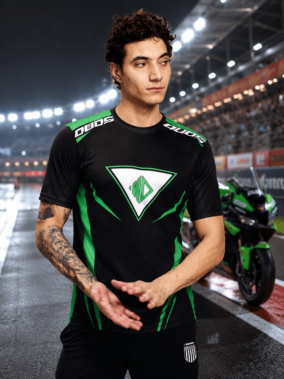 APEX RACING T-SHIRT BLACK on model in a racing environment, showcasing sports style and sleek design.