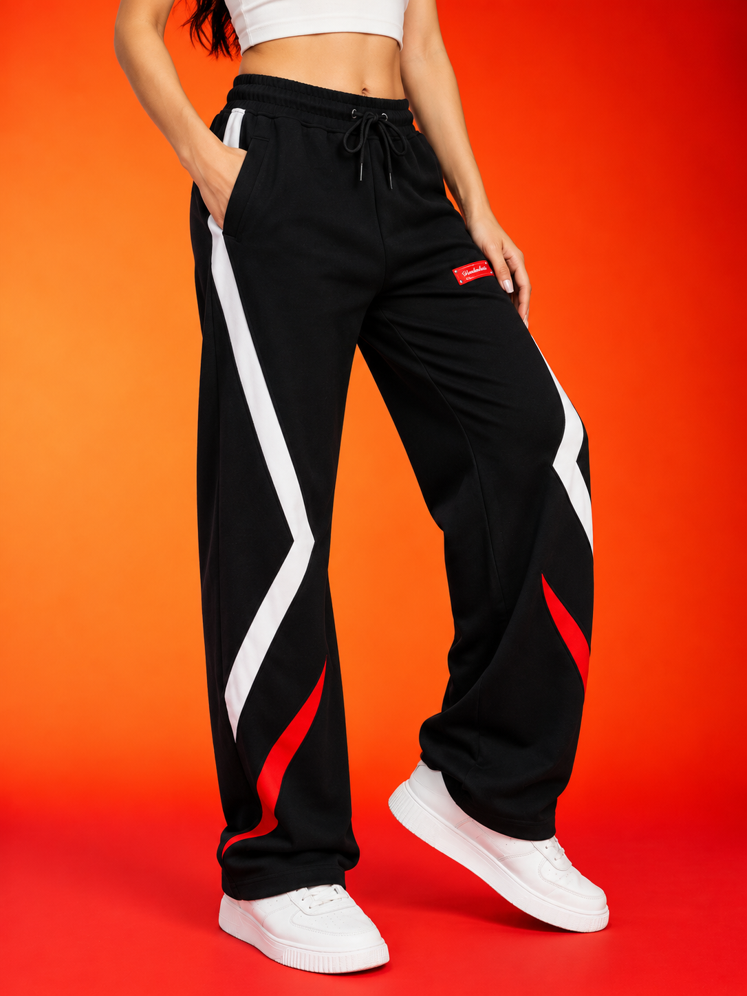 WOMEN METROPOLITAN JOGGERS BLACK WHITE RED STRIPE showcased in a stylish pose against an orange background.