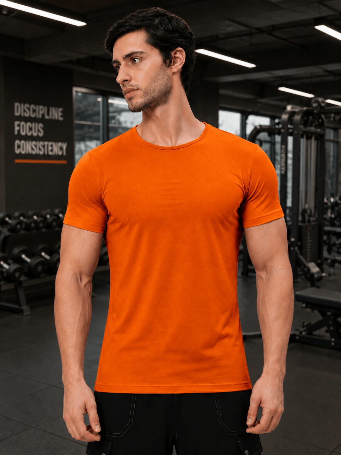 BEDROCK FIT REGULAR FIT T-SHIRT ORANGE worn by a male model in a gym setting with fitness equipment in background.