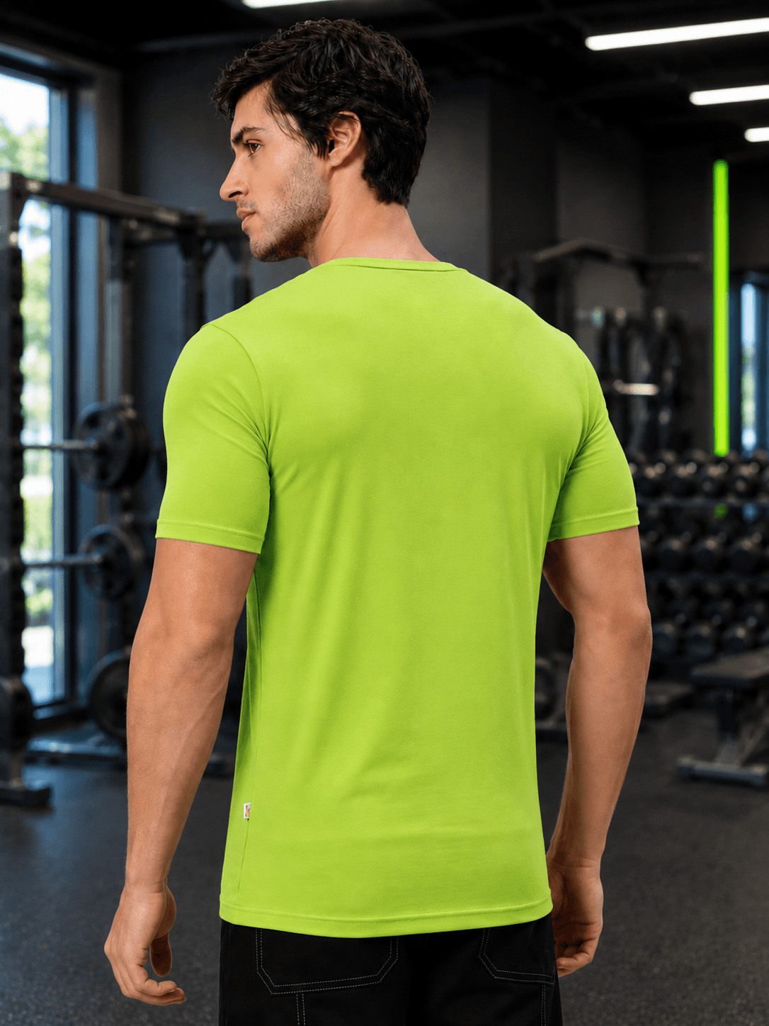 Man wearing BEDROCK FIT REGULAR FIT T-SHIRT NEON GREEN in a gym setting, showcasing the back of the shirt.