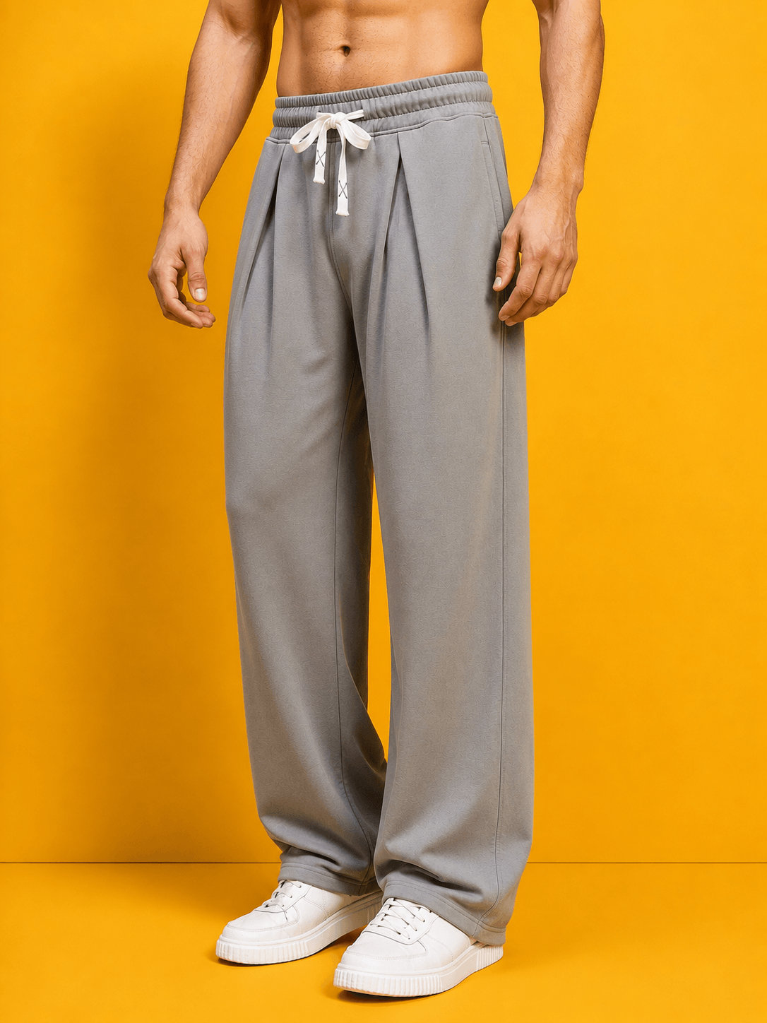 DRAPE TAILORED FIT JOGGERS GREY displayed on a model against a vibrant yellow background.