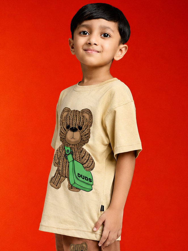 LITTLE EXPLORER TEDDY T-SHIRT FOR BOYS GIRLS BEIGE worn by a boy smiling against a bright red background.