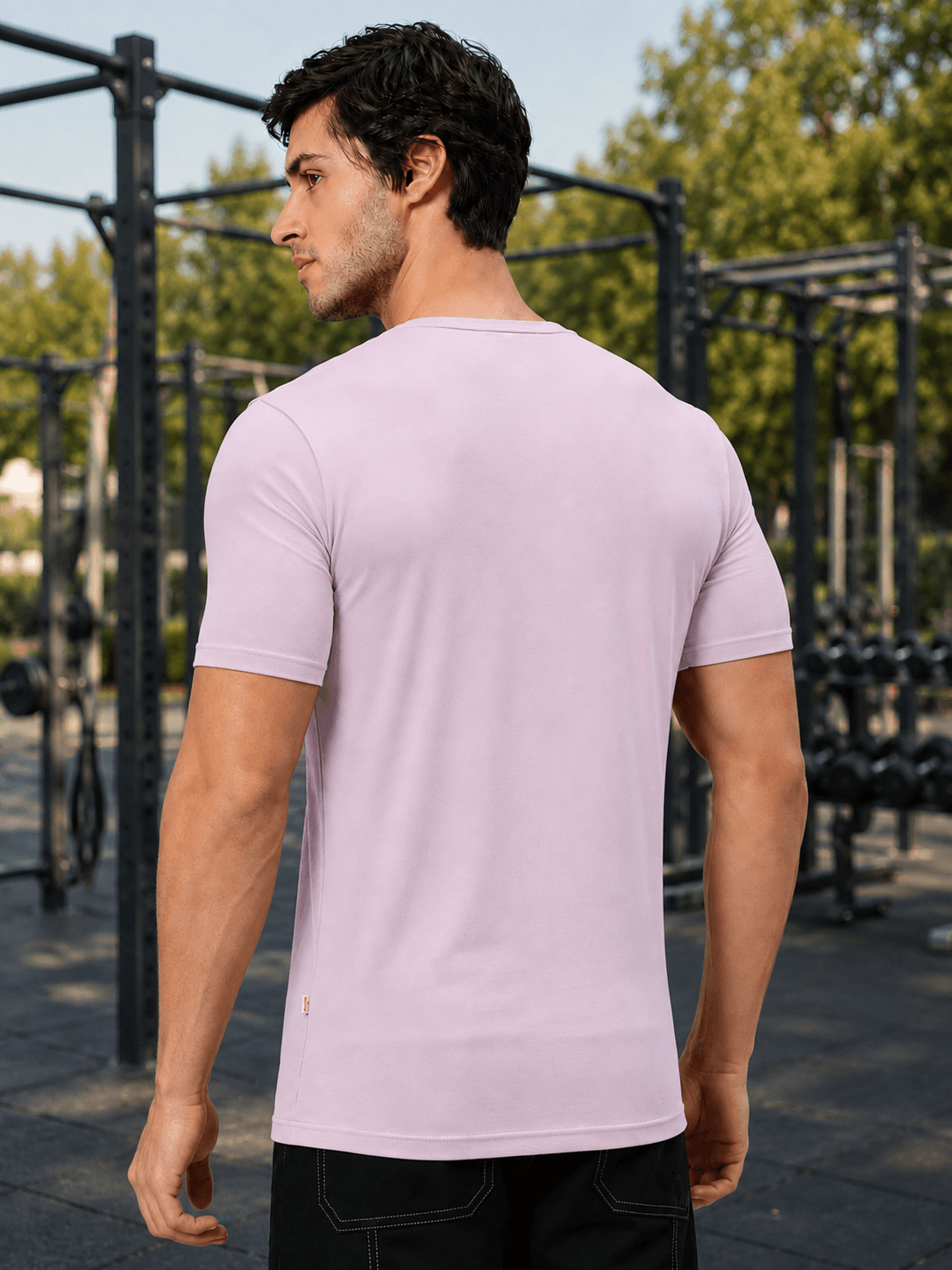Man wearing BEDROCK FIT REGULAR FIT T-SHIRT LILAC from the back in an outdoor gym setting.
