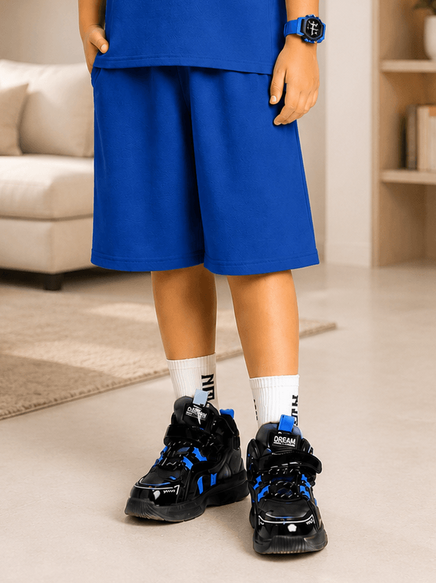 NEON RUSH SHORTS FOR BOYS GIRLS BLUE styled with sporty sneakers and socks, perfect for active summer play.