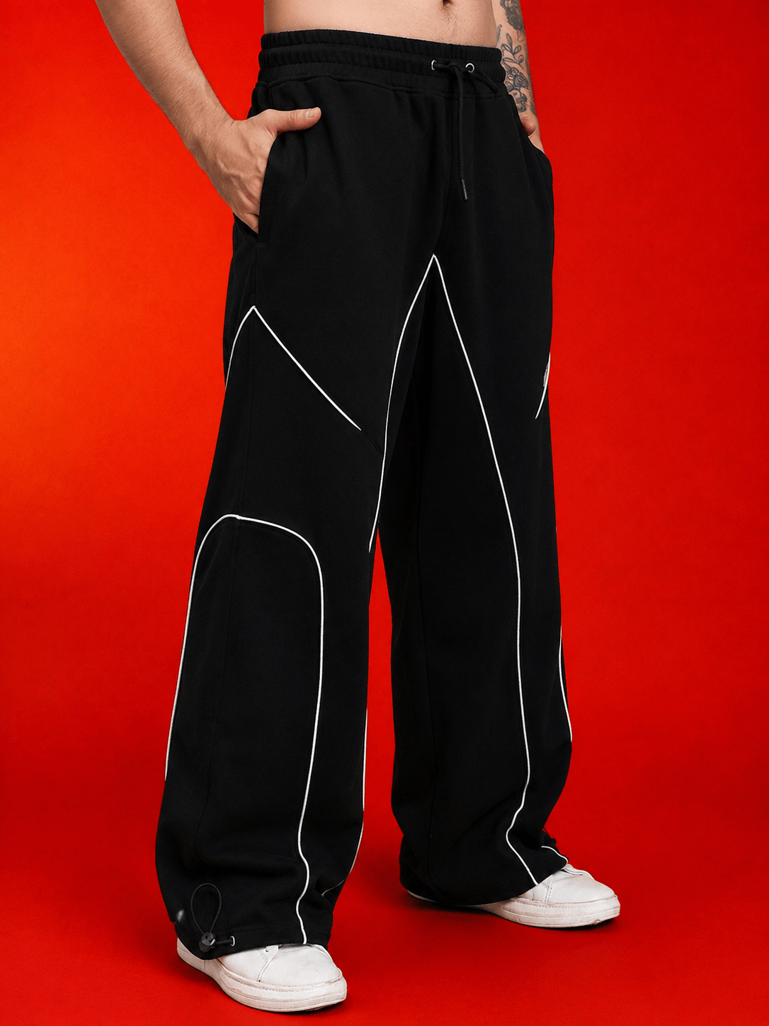 Man wearing SIGNATURE PIPING JOGGERS BLACK with contrast piping, showcasing relaxed fit and style in a vibrant background.