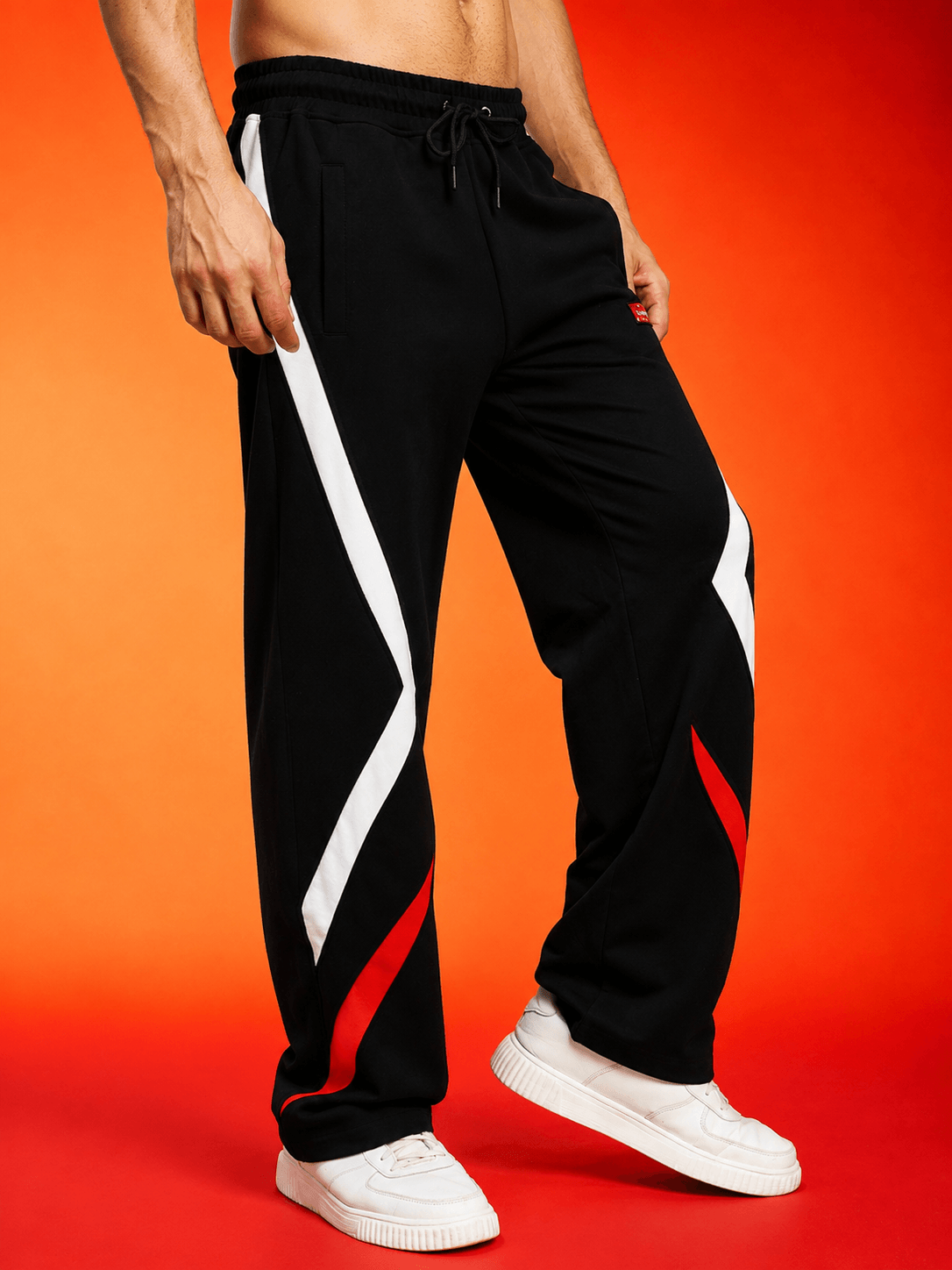 METROPOLITAN CONTRAST GRAPHIC JOGGERS BLACK MULTI showcased on a model against a vibrant orange background.